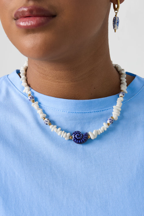 Ketting met stenen kralen, witte kralen met blauwe bloemetjes en statement schelp