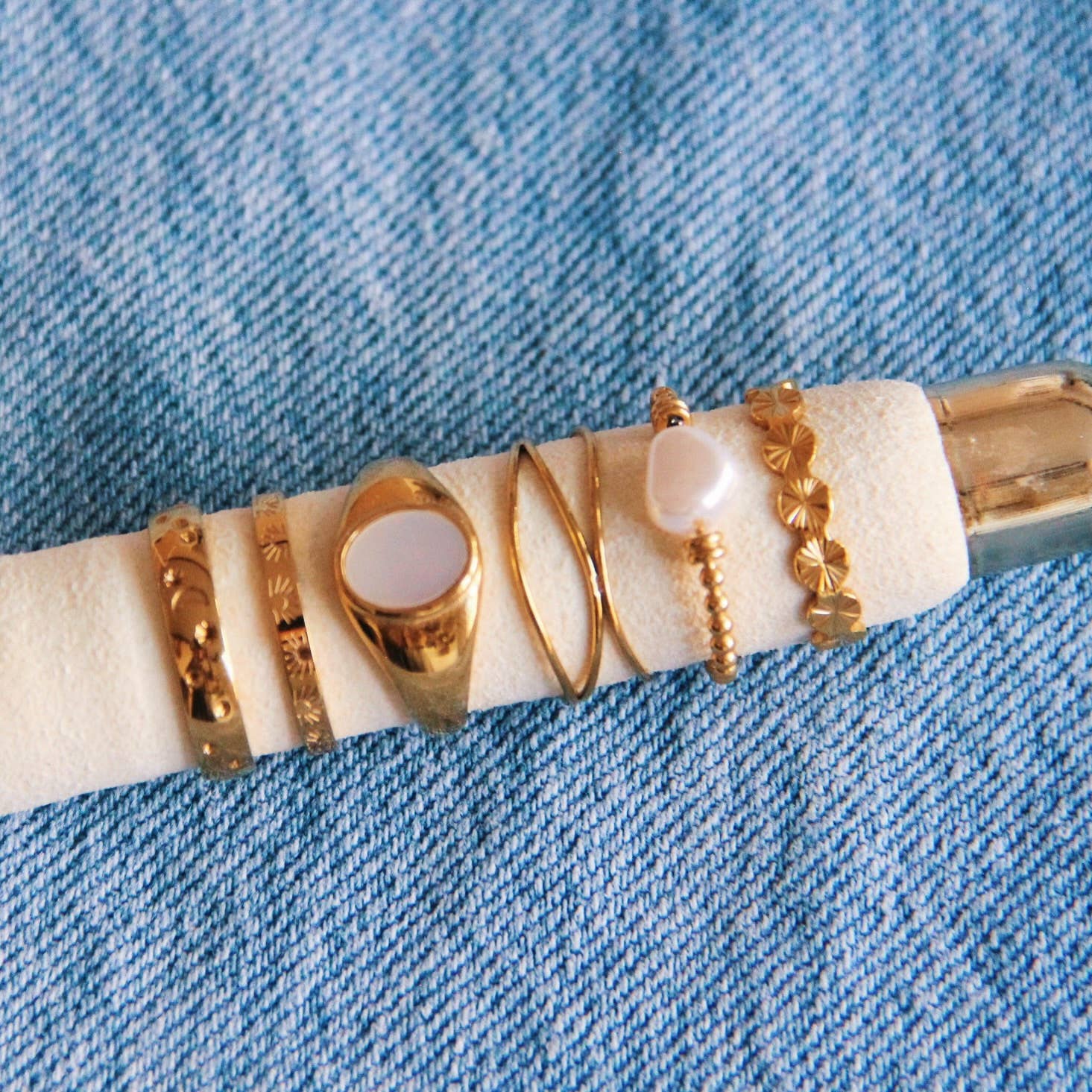 Set van gouden roestvrijstalen ringen met parel en minimalistisch design op blauwe jeans stof