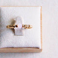 Gouden ring van roestvrij staal met lichtpaarse kubussteen op ringpresentatie. Dames sieraden.