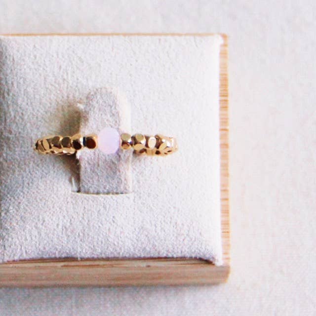 Gouden ring van roestvrij staal met lichtpaarse kubussteen op ringpresentatie. Dames sieraden.