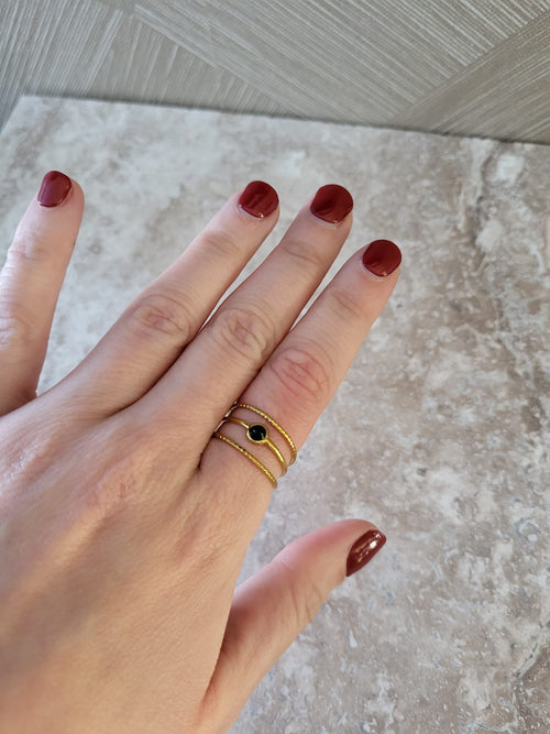 Gouden ring met zwarte natuursteen op vinger, elegante stainless steel damesring met detail van zwart steentje