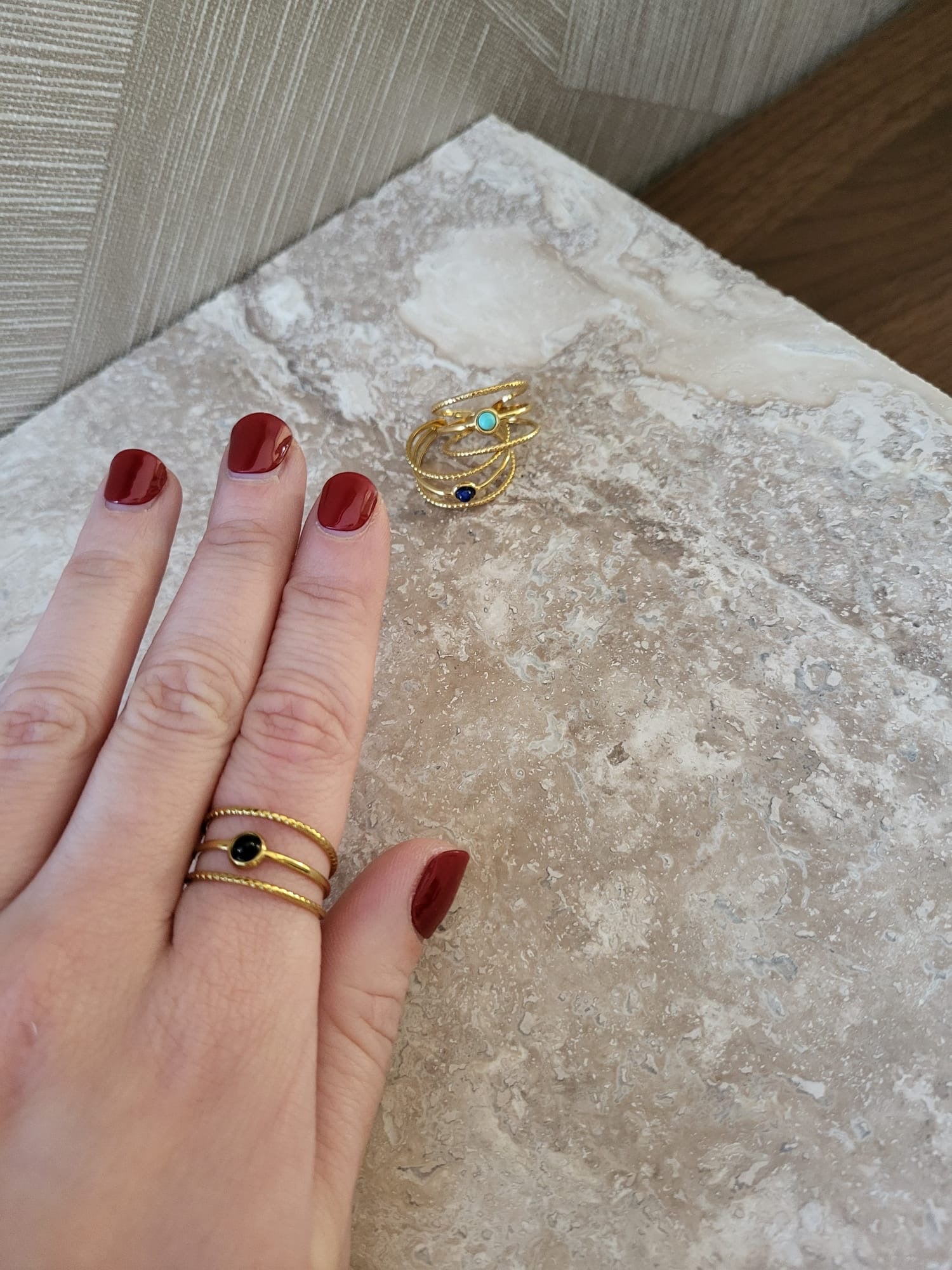 Gouden Aarya ring van stainless steel met zwarte natuursteen gedragen aan een vinger met rode nagellak