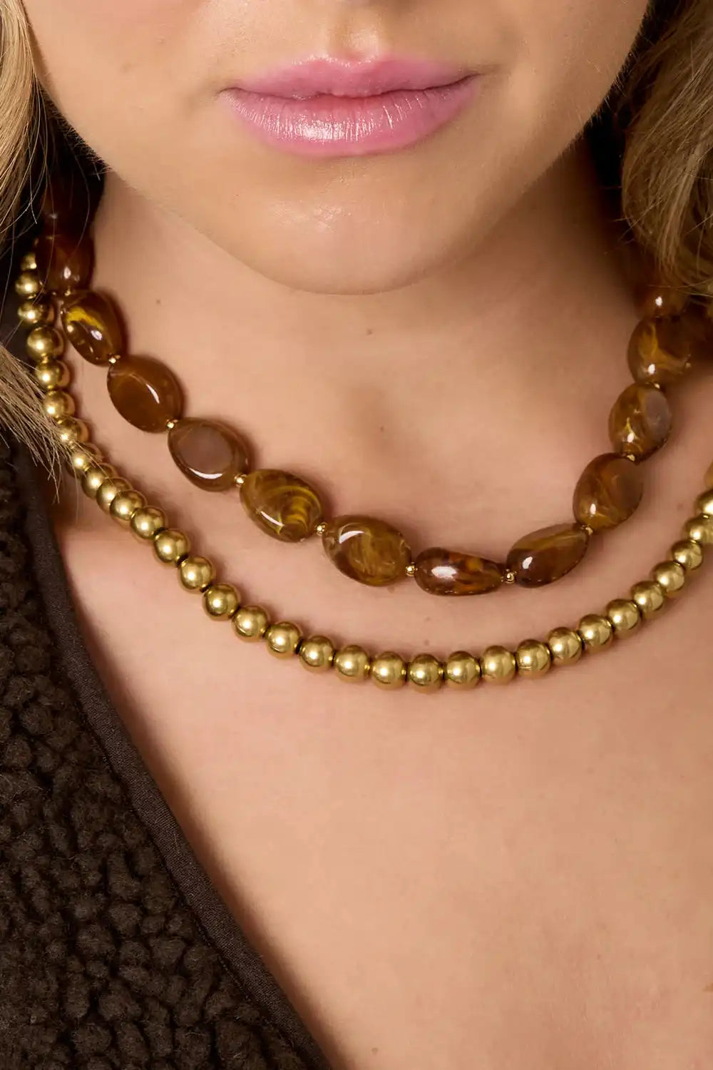 Amara Ruby Red ketting van roestvrij staal met glanzende bruine en gouden kralen om de hals van een vrouw