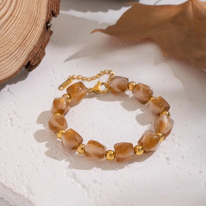 Elegante amberkleurige resin kralenarmband met gouden accenten en verstelbare sluiting. Perfect dames sieraad.
