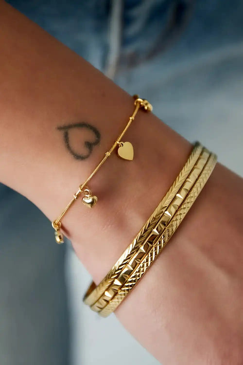 Gouden schakel armband met hartjes bedels en slanke gouden armbanden om de pols, van stainless steel.