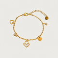 Gouden Amora armband van stainless steel met hartjes bedeltjes, parelmoer inleg en sprankelende steentjes.