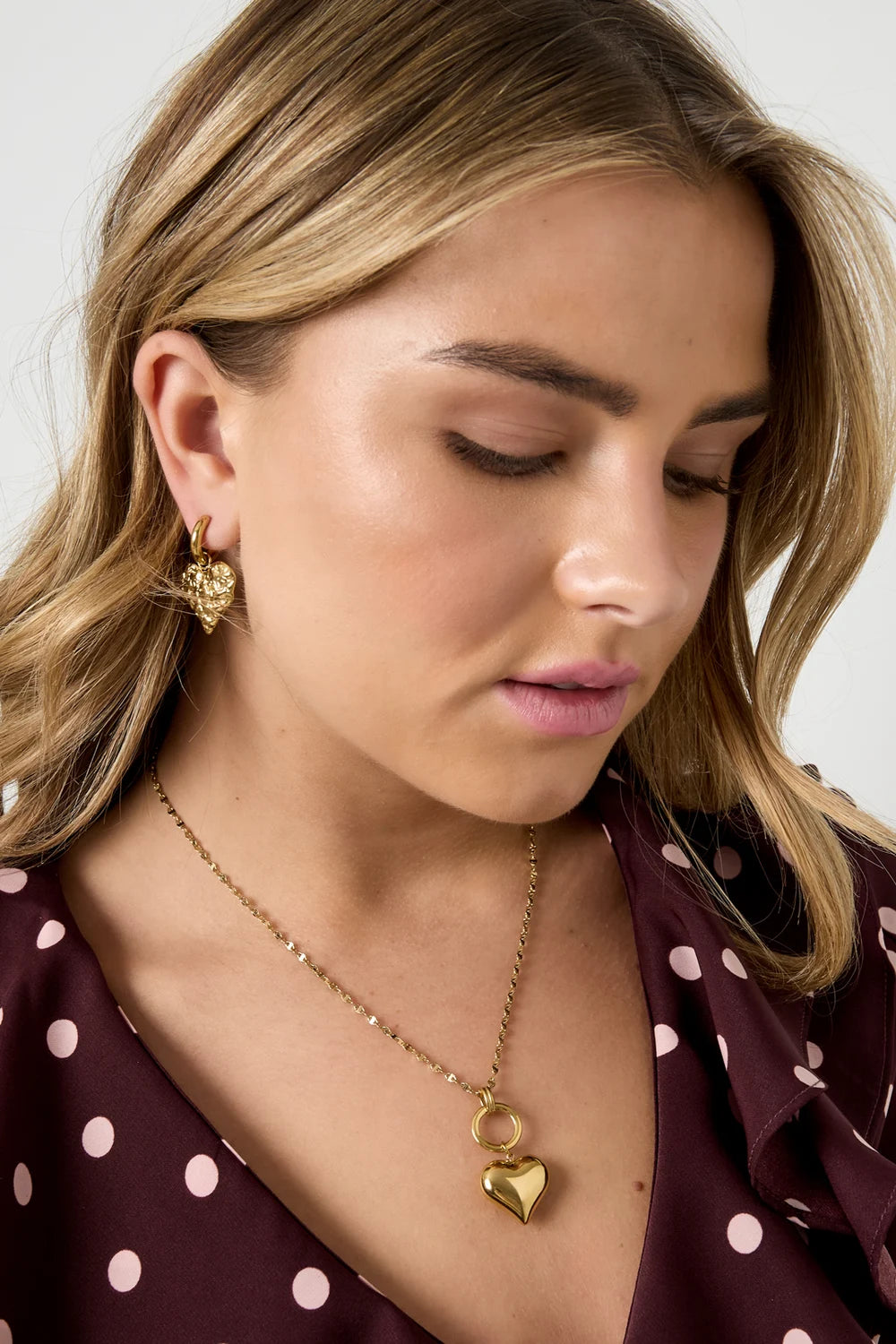 Model met gouden Amorea hartjes ketting van roestvrij staal en bijpassende oorbellen, prachtig sieraad.