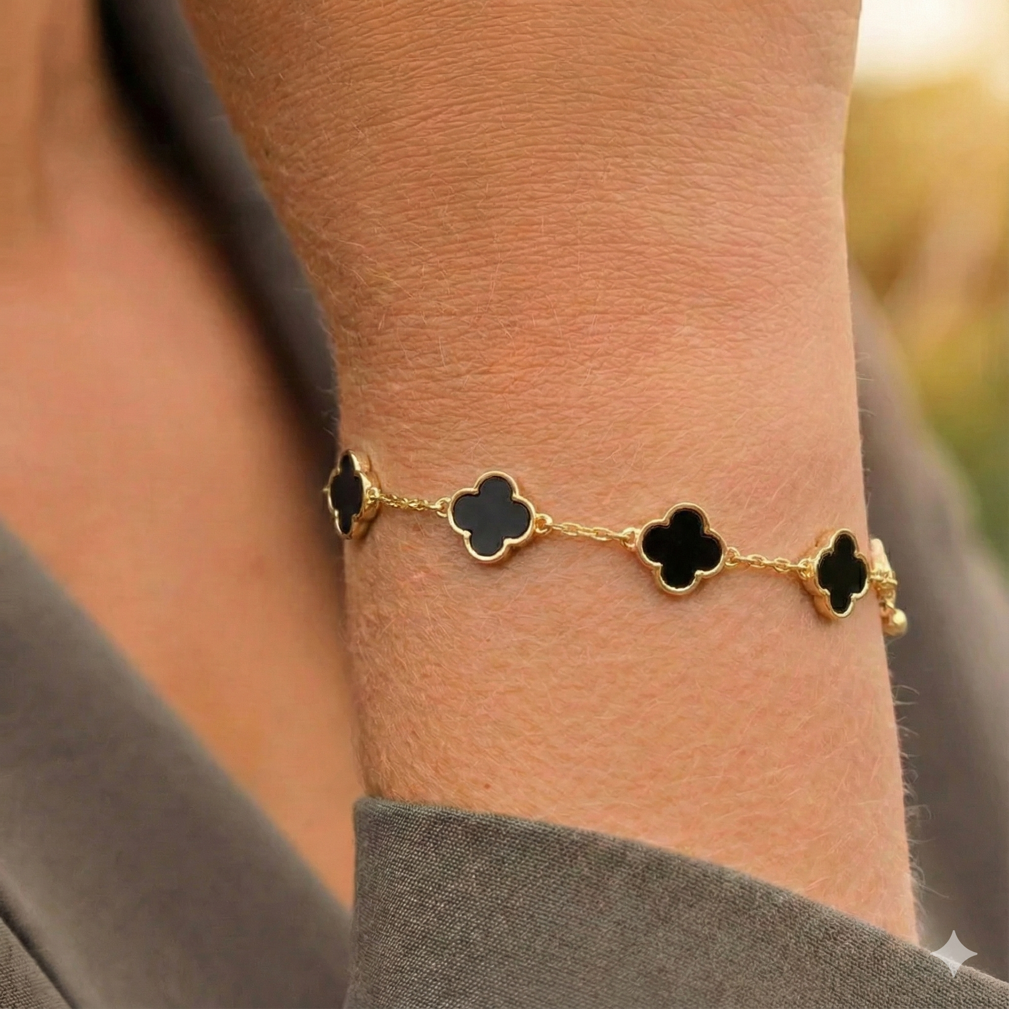 Goudkleurige stalen armband met zwarte klavertjes vier, perfect voor dames sieraden en accessoires.