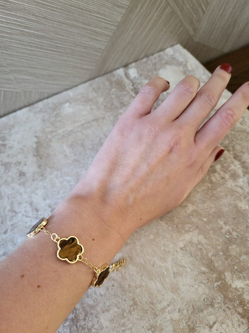 Gouden Belle armband van roestvrij staal met bruine bloemvormige schakels aan een pols, elegant sieraad