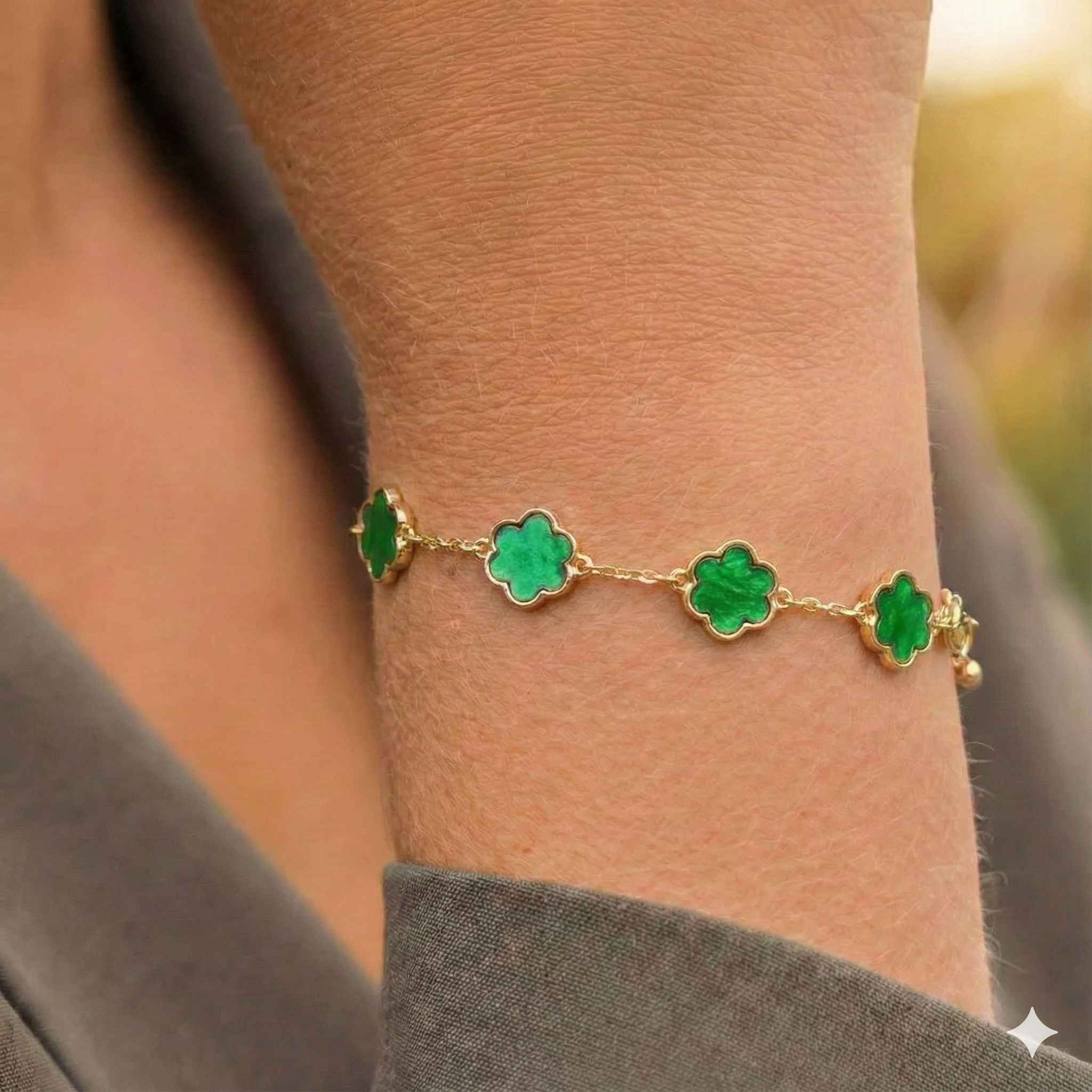 Gouden roestvrijstalen armband met groene klavervormige bedeltjes om een arm