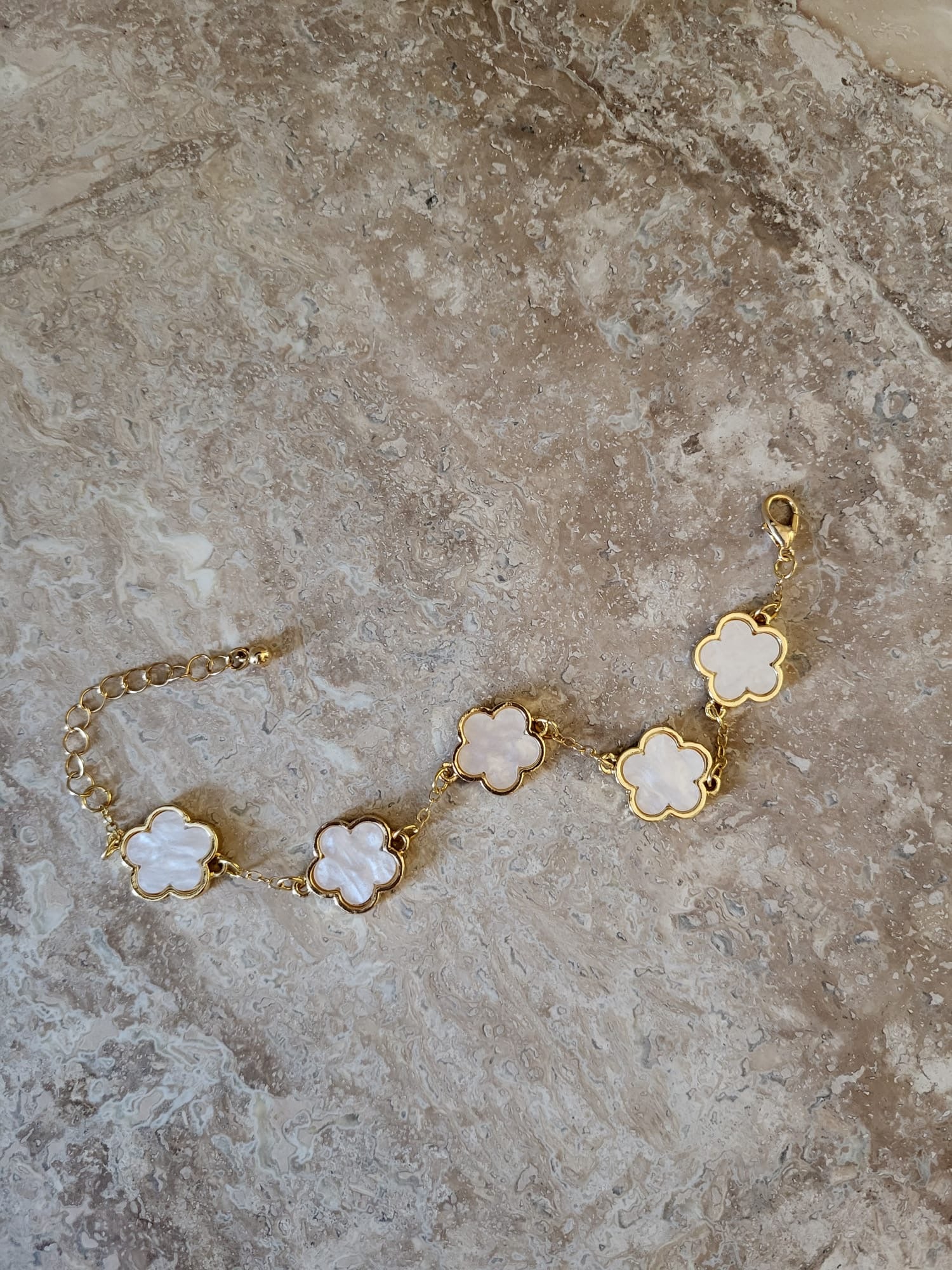 Gouden schakelarmband met witte klavertjes vier motiefjes, gemaakt van roestvrij staal.