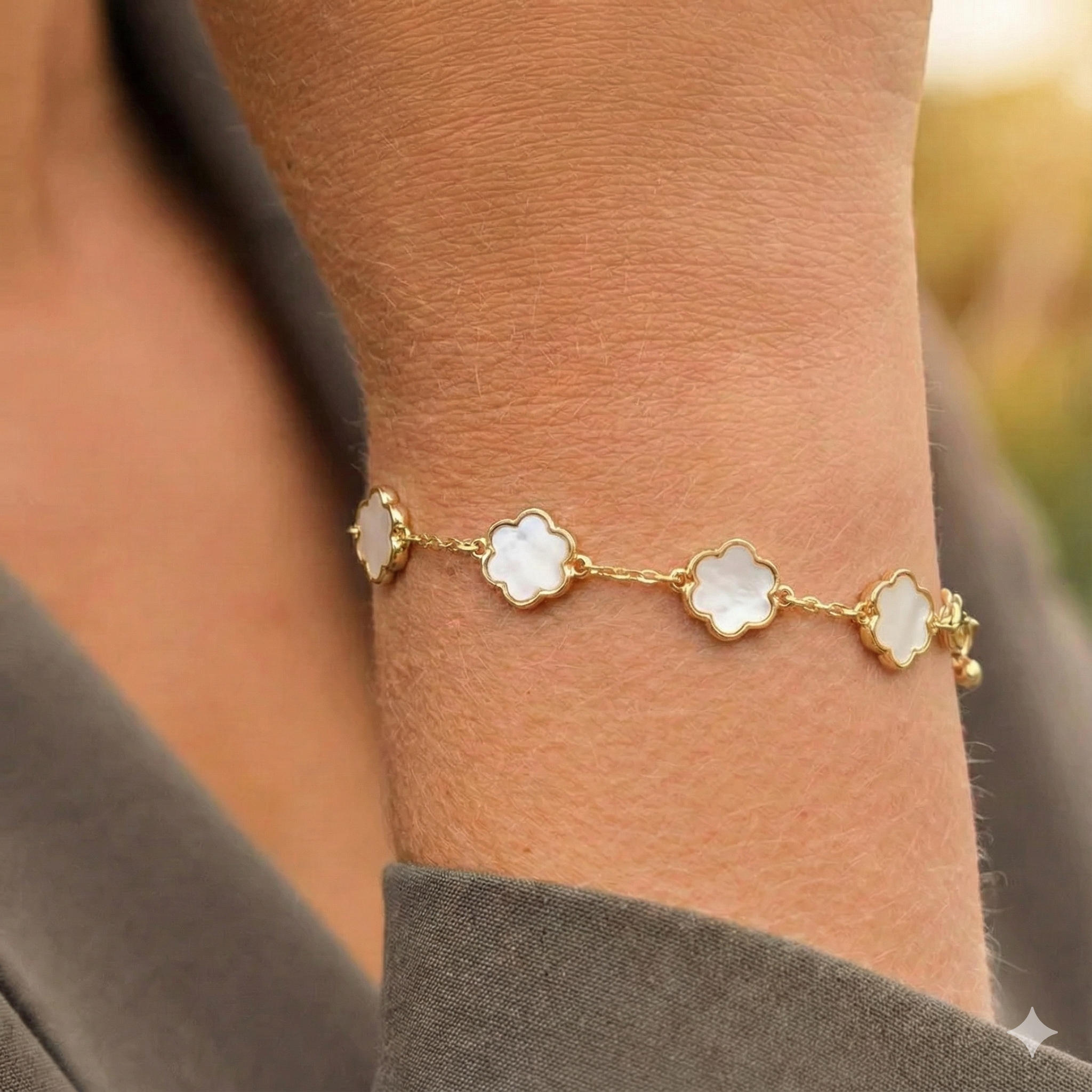 Goudkleurige Belle armband van roestvrij staal met witte bloemmotief schakels op een damesarm