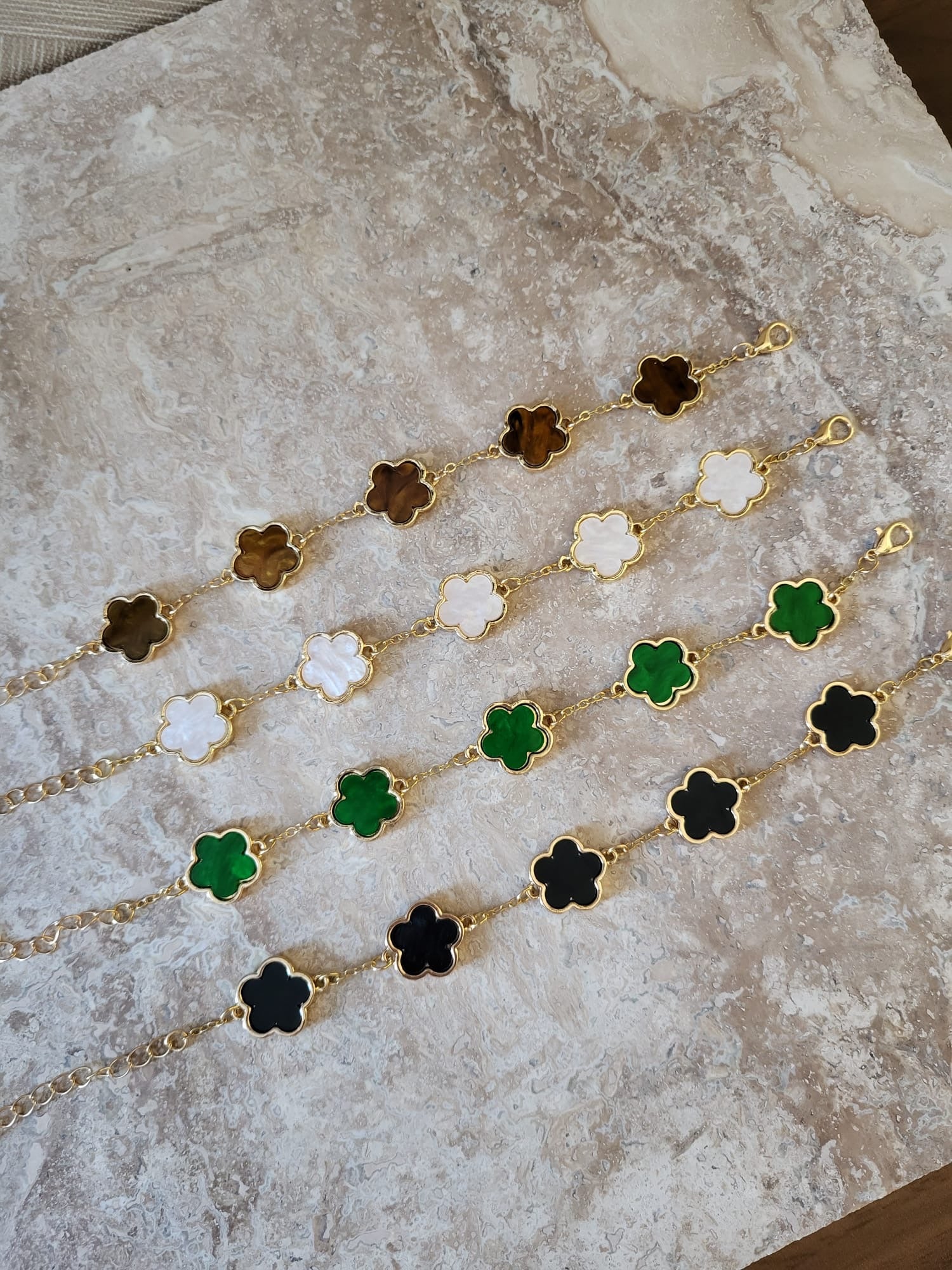 Belle armbanden in wit, bruin, groen en zwart met klaverhangers van roestvrij staal