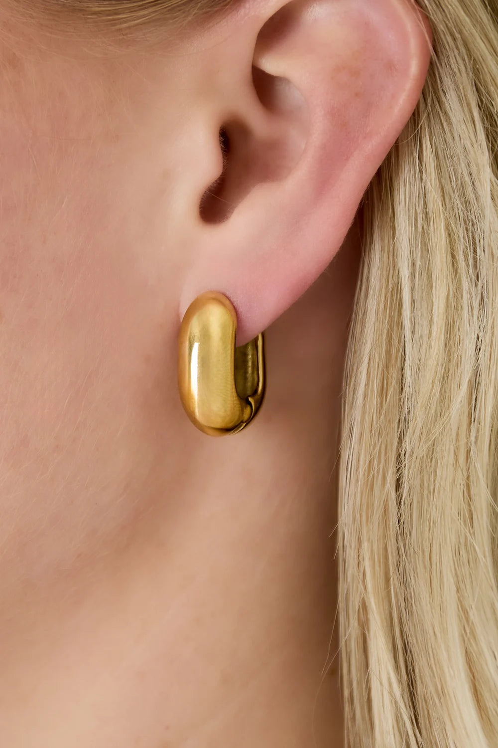 Big Hoop gouden oorbellen van stainless steel, gedragen door een vrouw met blond haar, gedetailleerde oorbel close-up
