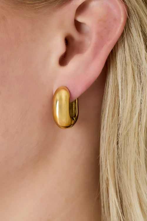 Big Hoop gouden oorbellen van stainless steel, gedragen door een vrouw met blond haar, gedetailleerde oorbel close-up