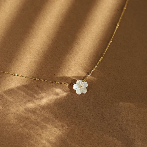Gouden stainless steel ketting met hanger van witte bloem. Elegante halsketting met bloesem bedel. Moederparel sieraad.