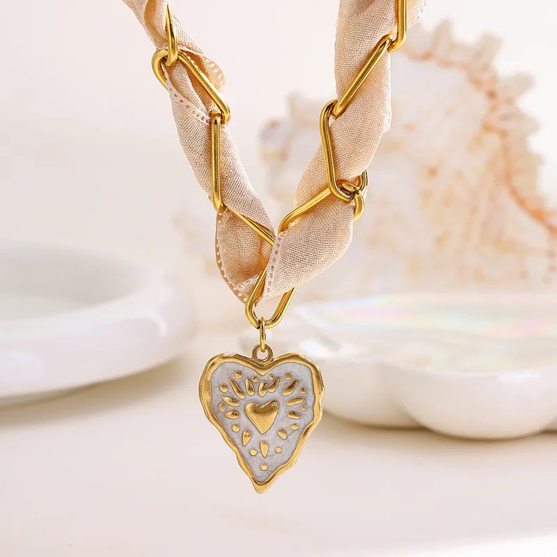 Celeste beige ketting met gouden schakels, geknoopt lint en unieke wit-gouden hart hanger van stainless steel.