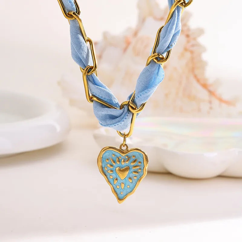 Celeste ketting met blauw lint en een rvs hart hanger, goudkleurig en aqua blauw emaille.