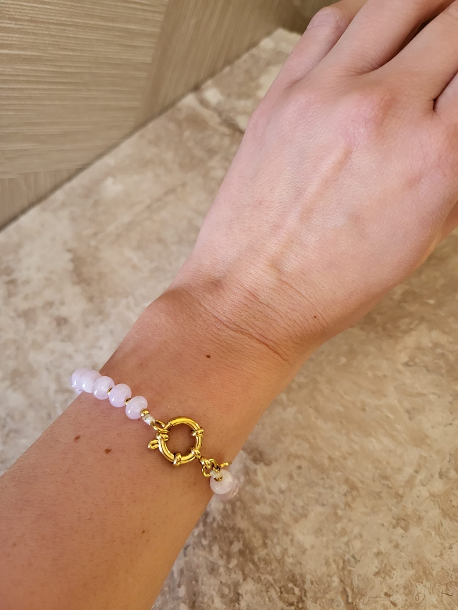 Clarisa armband met lichtroze natuurstenen kralen en een gouden sluiting om een pols