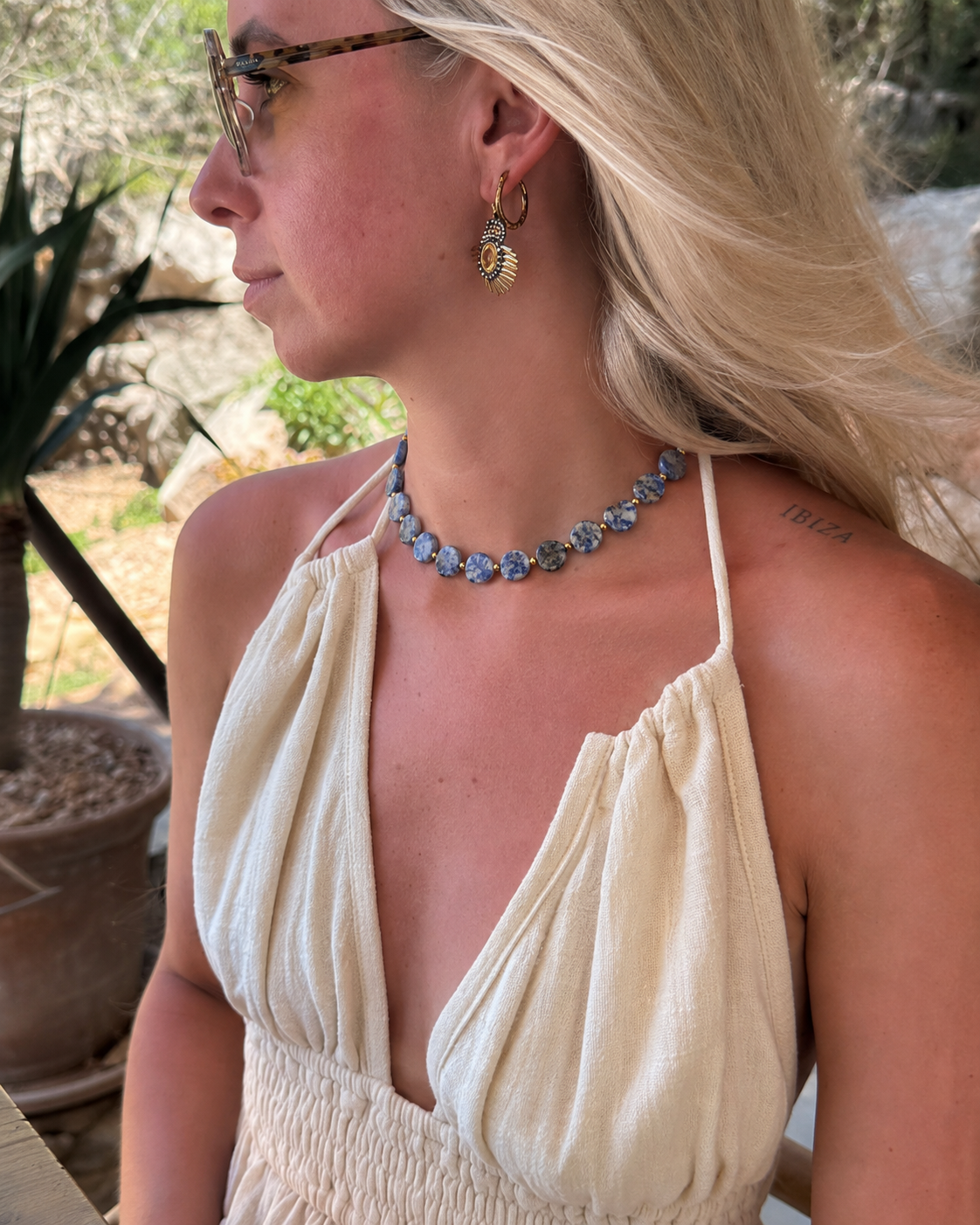 Vrouw draagt Elena stainless steel ketting met blauwe kralen en goudkleurige details om de hals, trendy sieraad