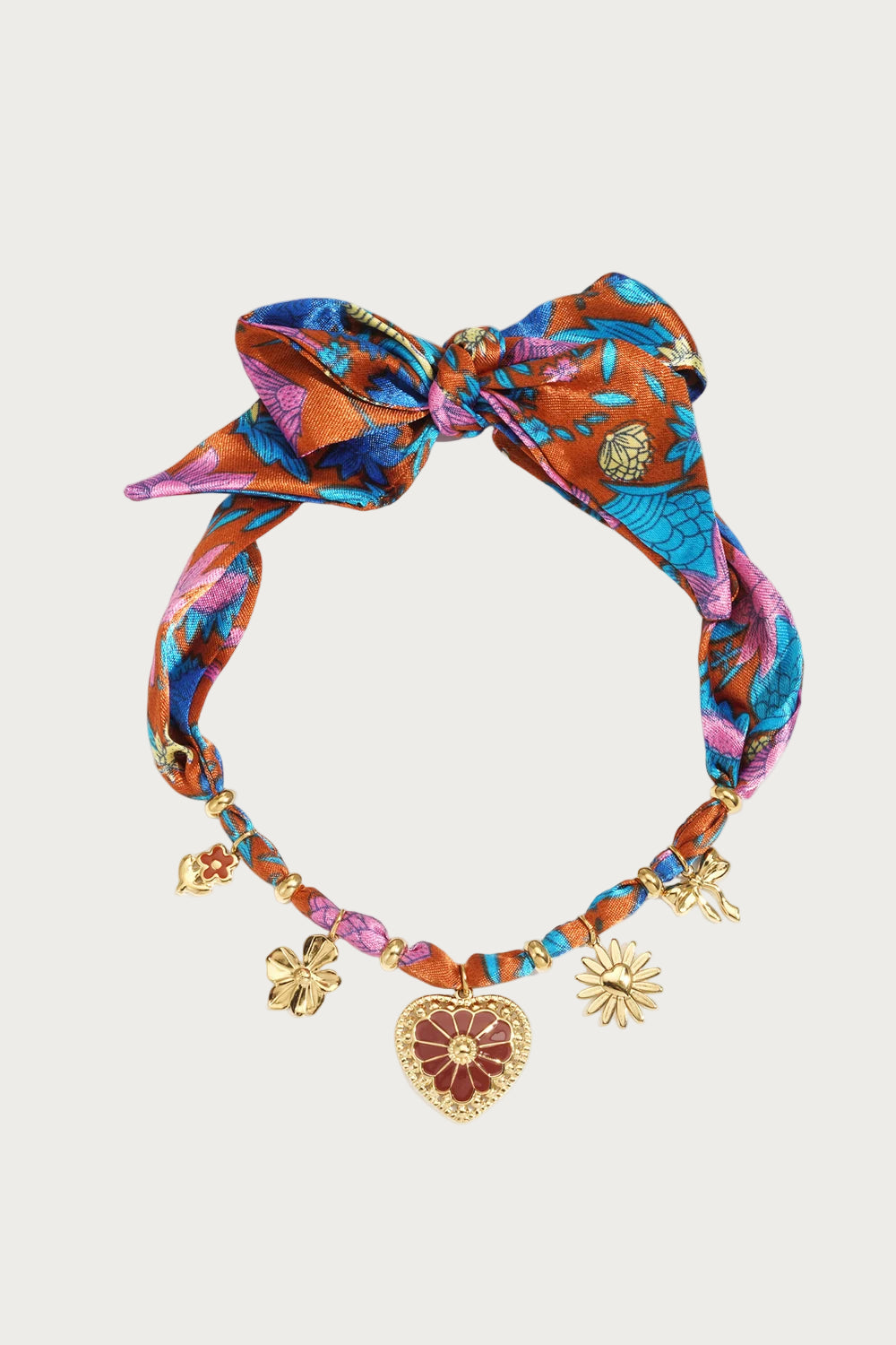 Multicolor statement ketting met stoffen strik en diverse gouden bedels, waaronder een hart en bloemen