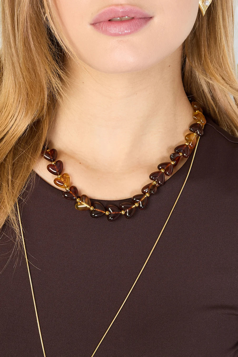 Vrouw met Milena groene hartjes ketting van roestvrij staal, gecombineerd met een lange gouden ketting.