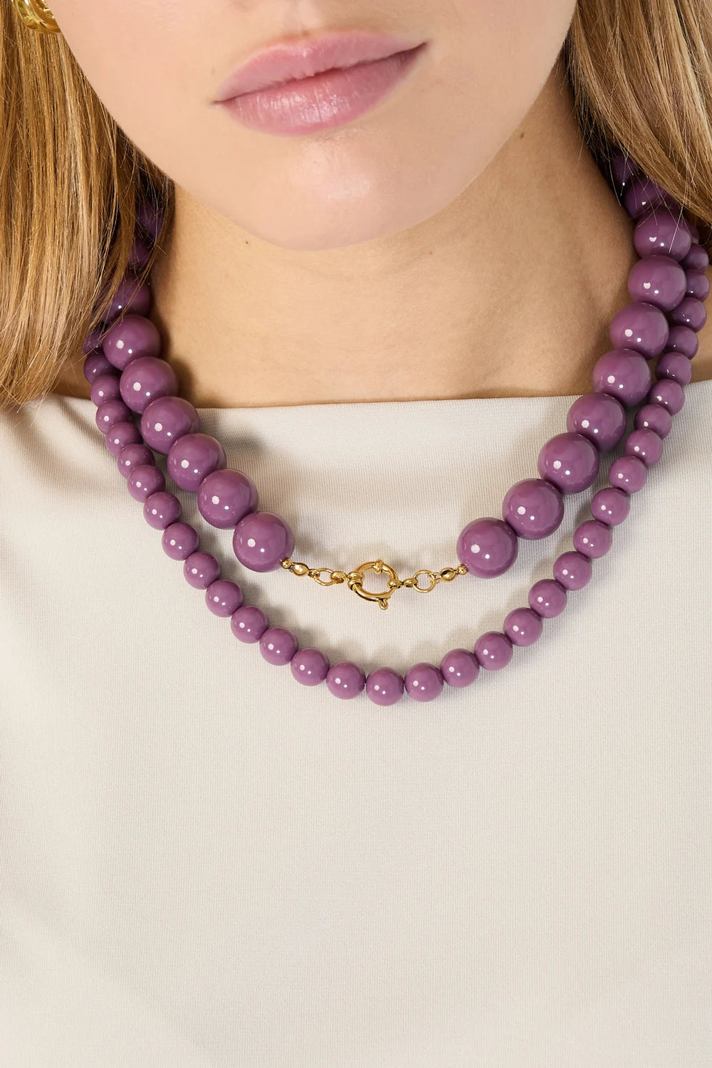 Mooie Mira ketting paarse kralen, een dubbele rij roestvrijstalen sieraden om de nek van een vrouw.