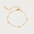 Gouden stainless steel armband met lichtroze en parelmoer bloemetjes en kleine gouden balletjes.