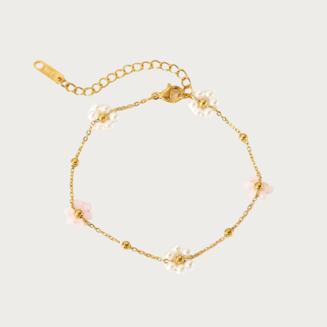 Gouden stainless steel armband met lichtroze en parelmoer bloemetjes en kleine gouden balletjes.
