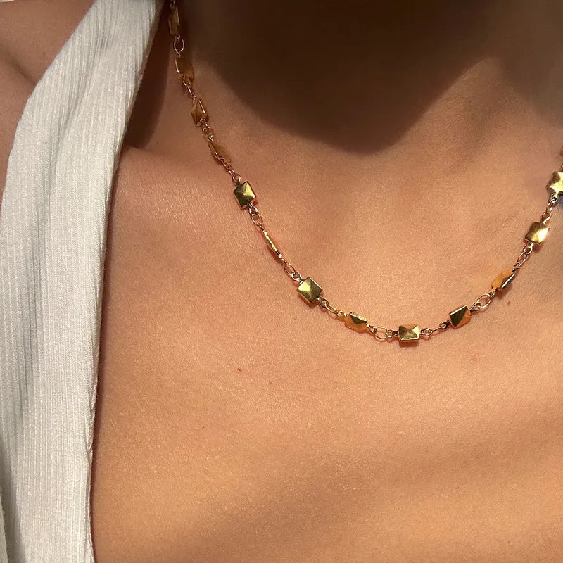 Nola gouden ketting van stainless steel met vierkante schakels op de hals van een vrouw, stijlvolle sieraden