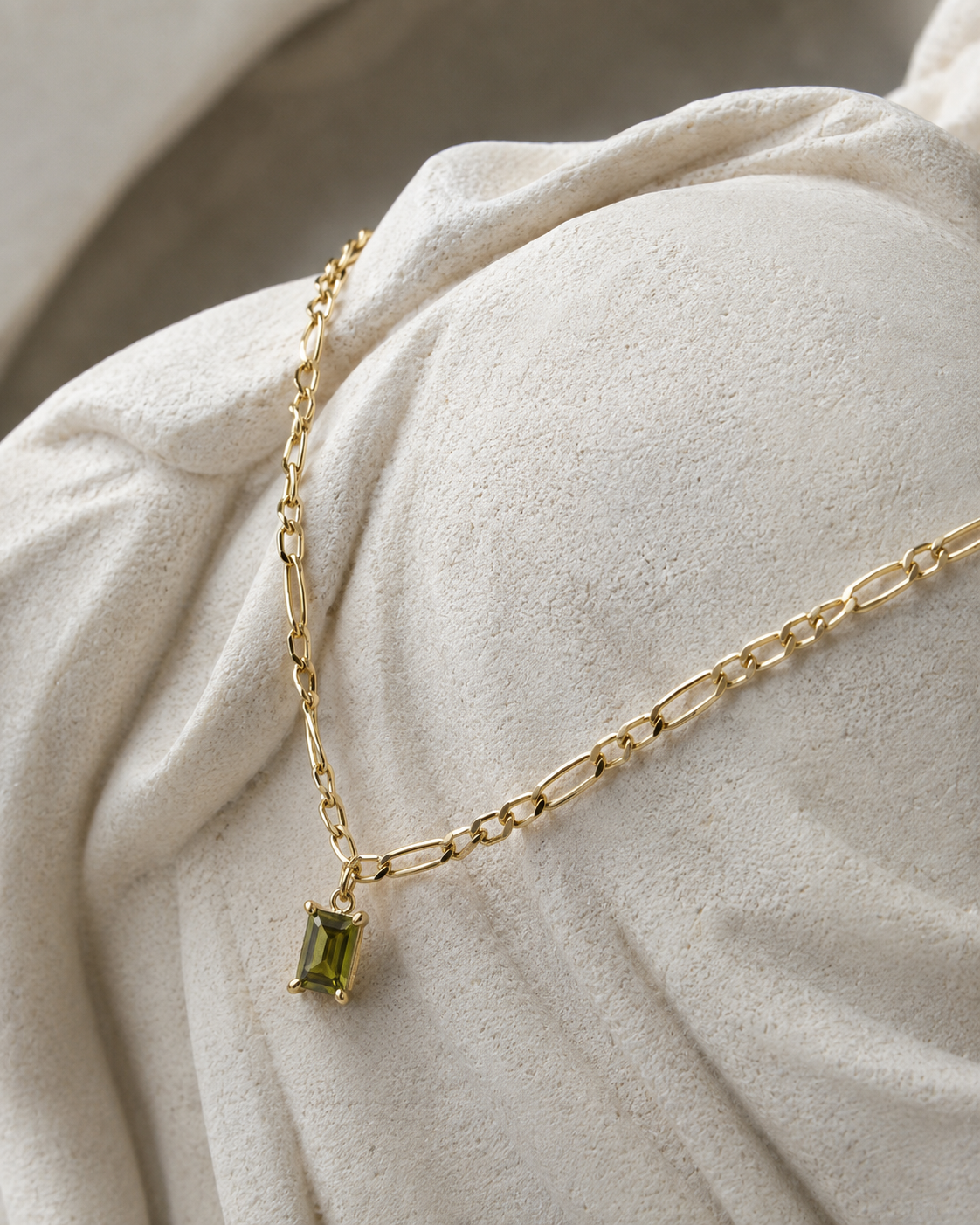 Gouden figaro ketting van stainless steel met rechthoekige olijfgroene steen, hangend aan de ketting.
