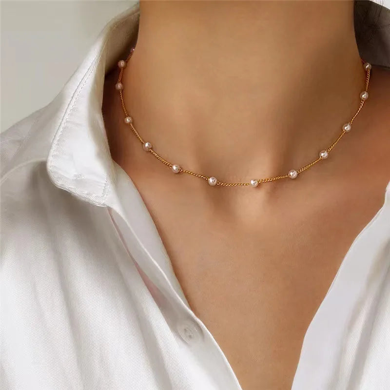 Fijne gouden ketting met kleine imitatie parels gedragen om de nek, elegant collier voor dames.