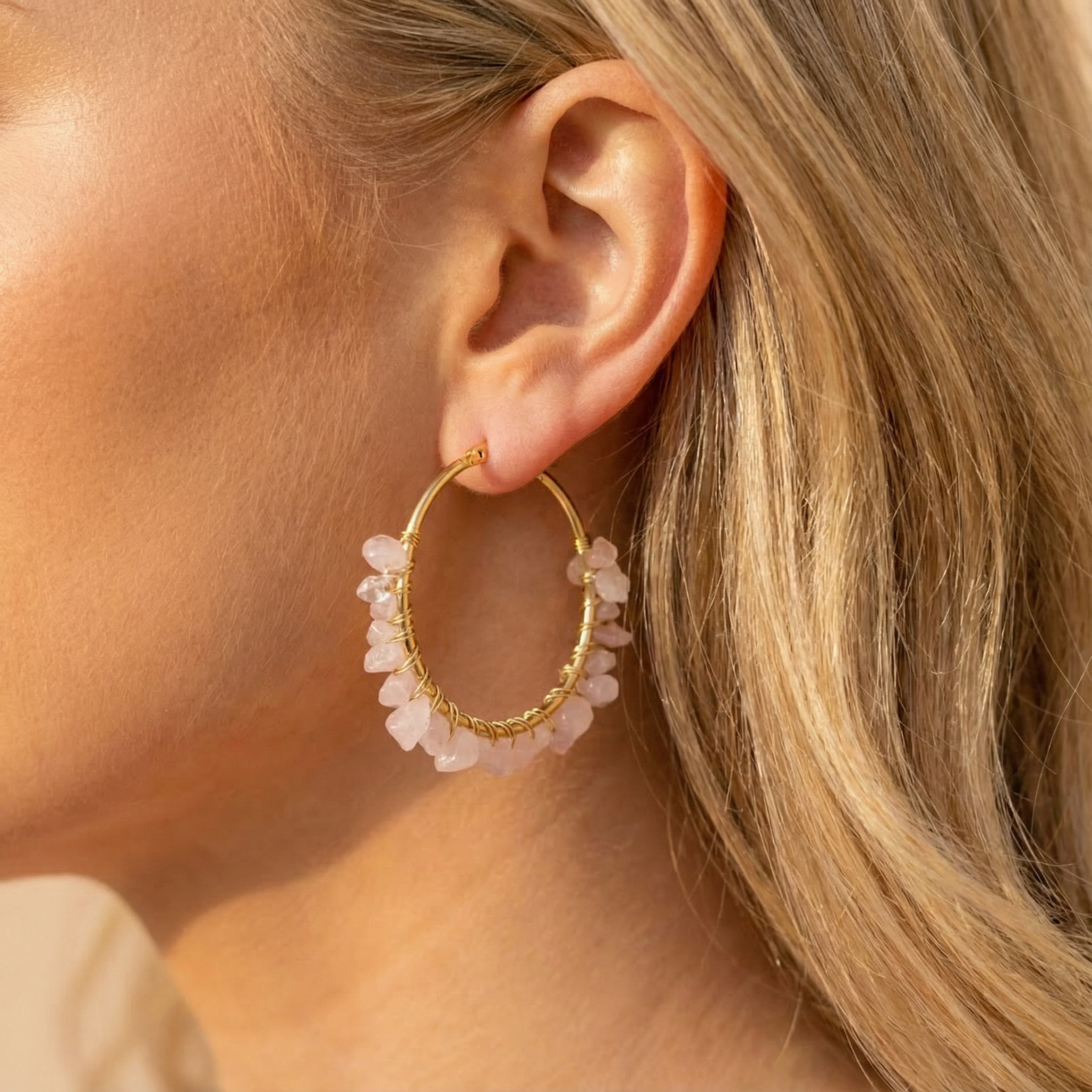 Stainless steel oorbellen met roze natuursteen kristallen, gouden hoops gedragen door blondharige vrouw