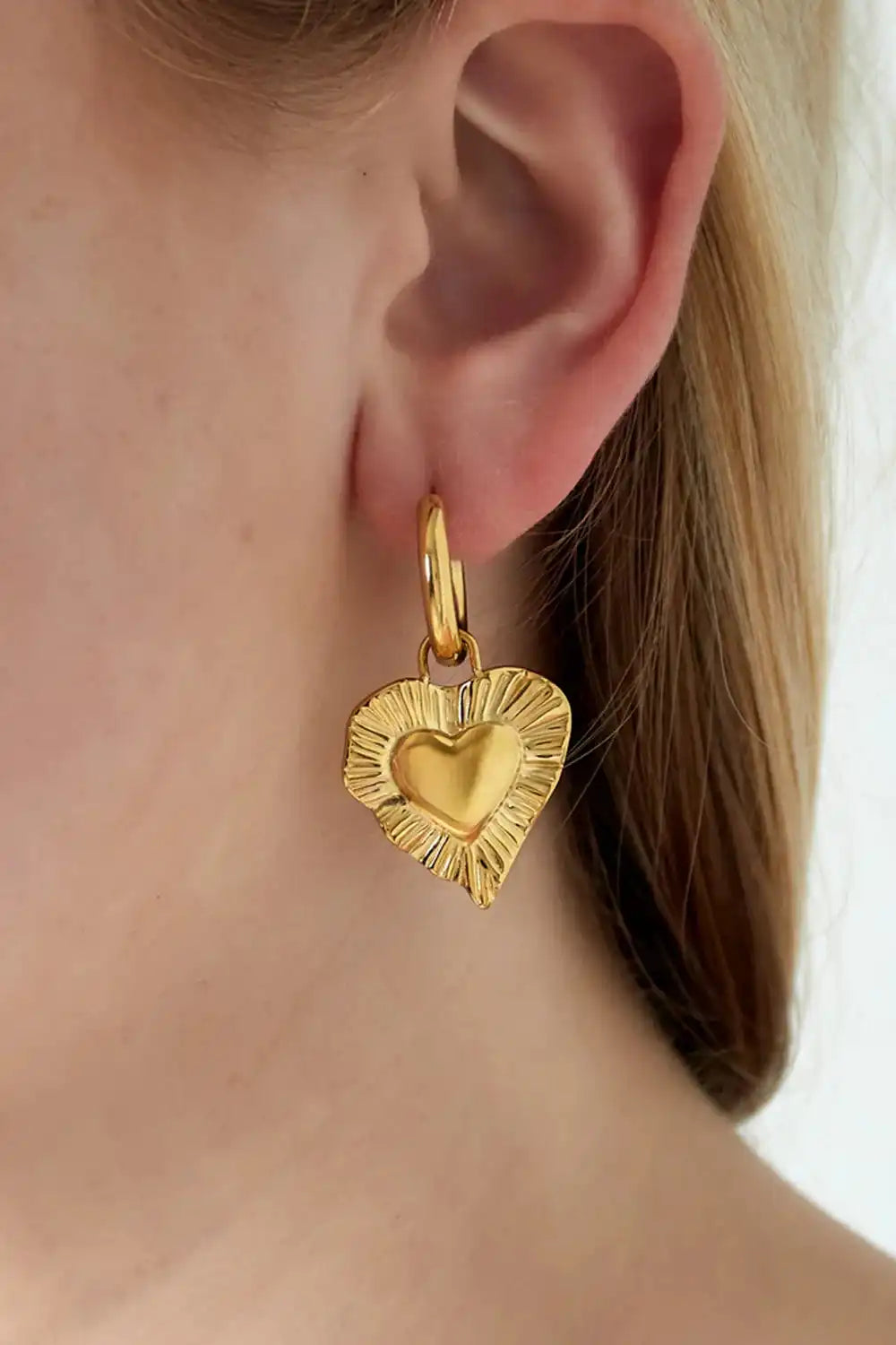 Radiant Heart Silver oorbel gedragen in oor, toont opvallende hartvormige bedel in goudkleurige variant voor stijlvolle ear party look.