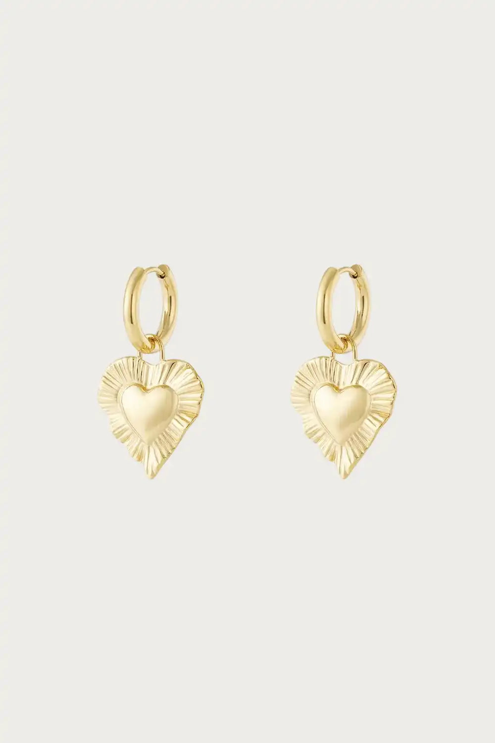 Radiant Heart – Oorbellen – Stainless Steel kopen? Goudkleurige oorbellen met hartvormige hanger en zonnestraalreliëf, perfect als statement sieraad.