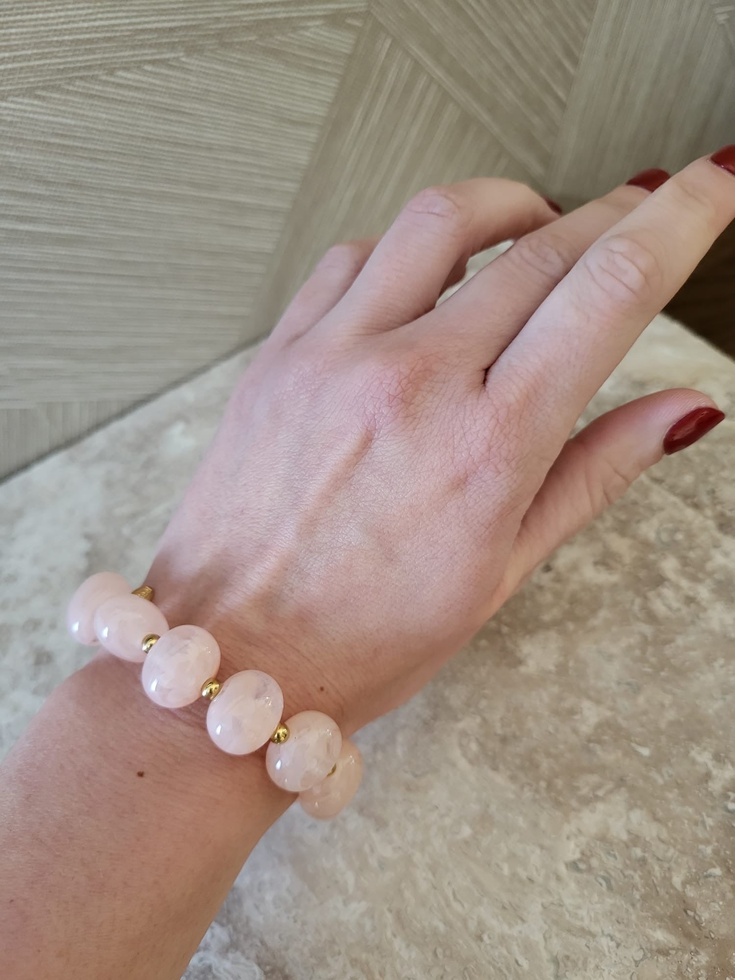 Rosalie armband met roze kralen en gouden stainless steel accenten om de pols van een vrouw