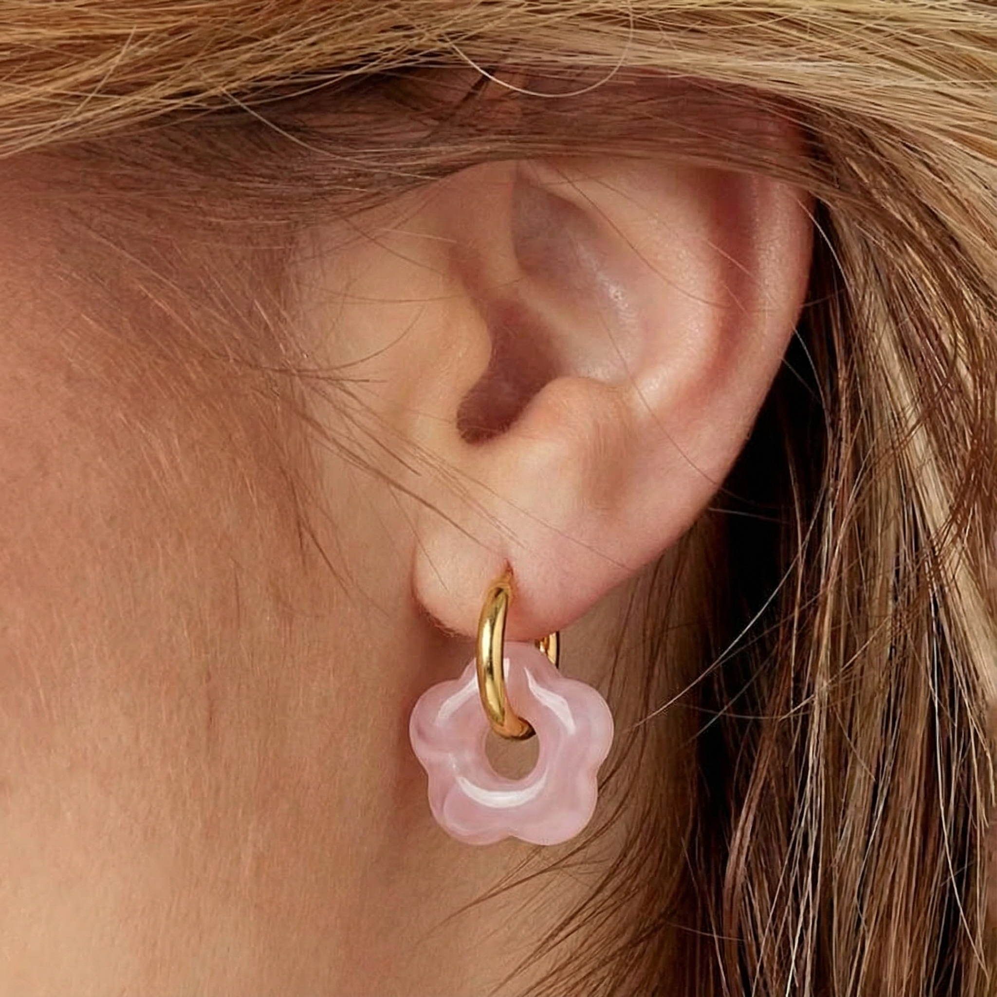 Rosy oorbellen met roze bloemhanger en gouden ringen gedragen door model