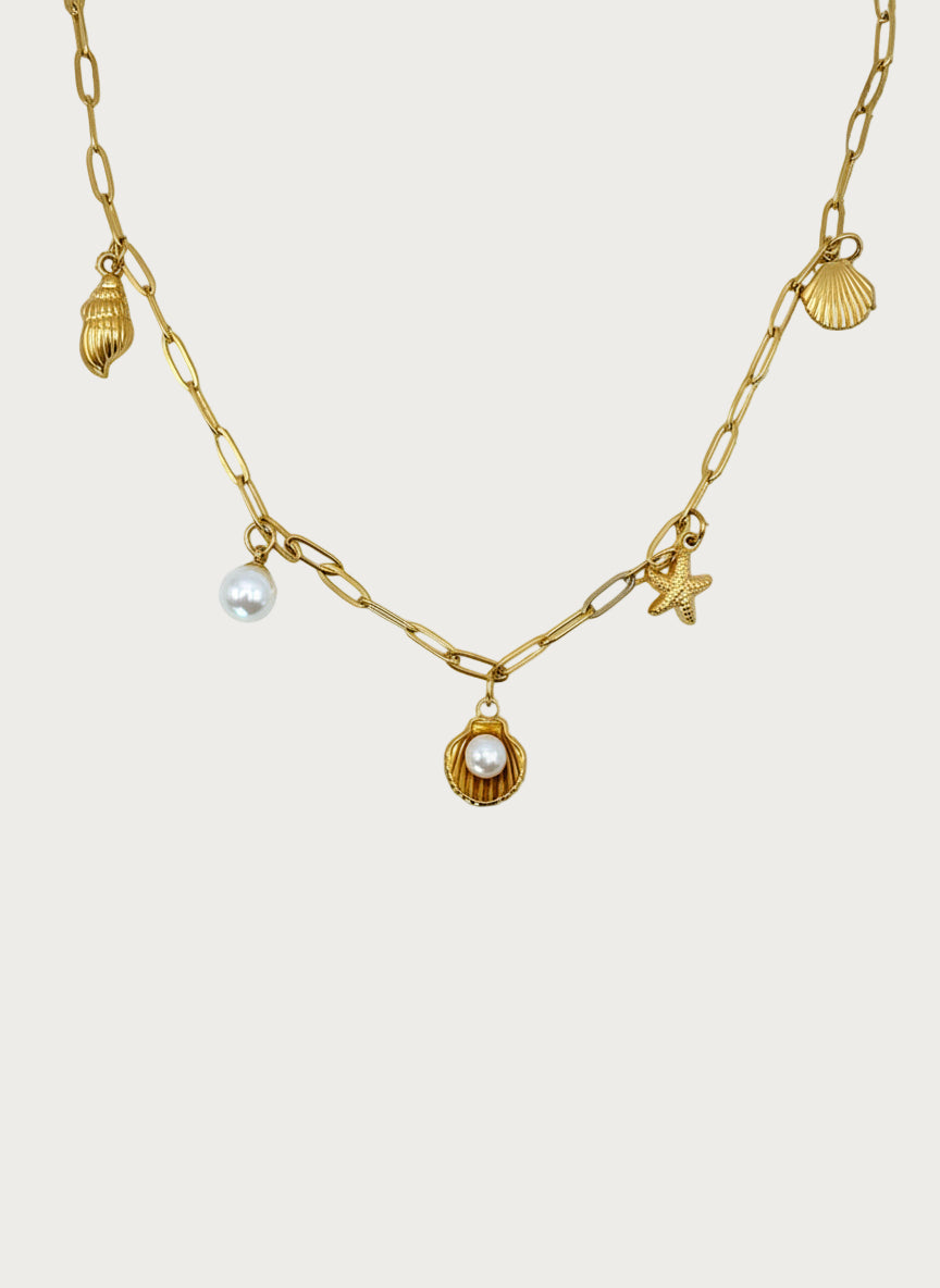 Gouden roestvrijstalen ketting met zeeschelpen, zeewier en parelhanger. Seaside ketting met parel en schelpdetails.
