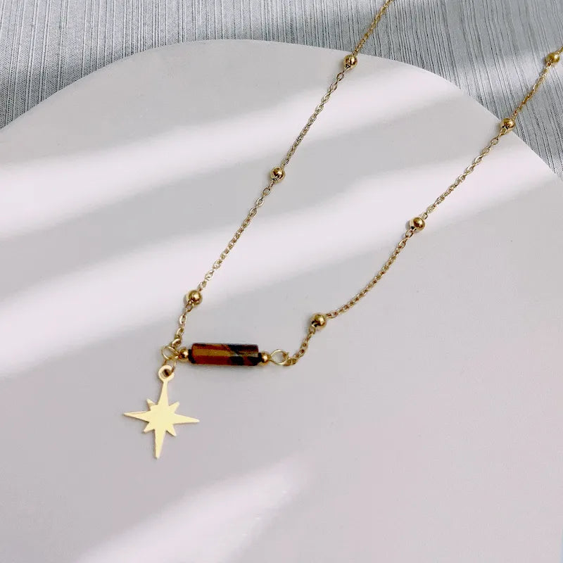 Gouden Solène ketting van stainless steel met bruine staafkraal en gouden kompaster ster hanger