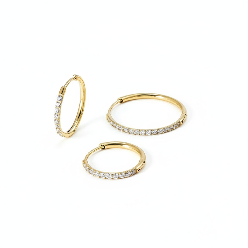 Drie gouden oorbellen van roestvrij staal met kleine, glinsterende steentjes, perfect als subtiele sieradenaccessoire.
