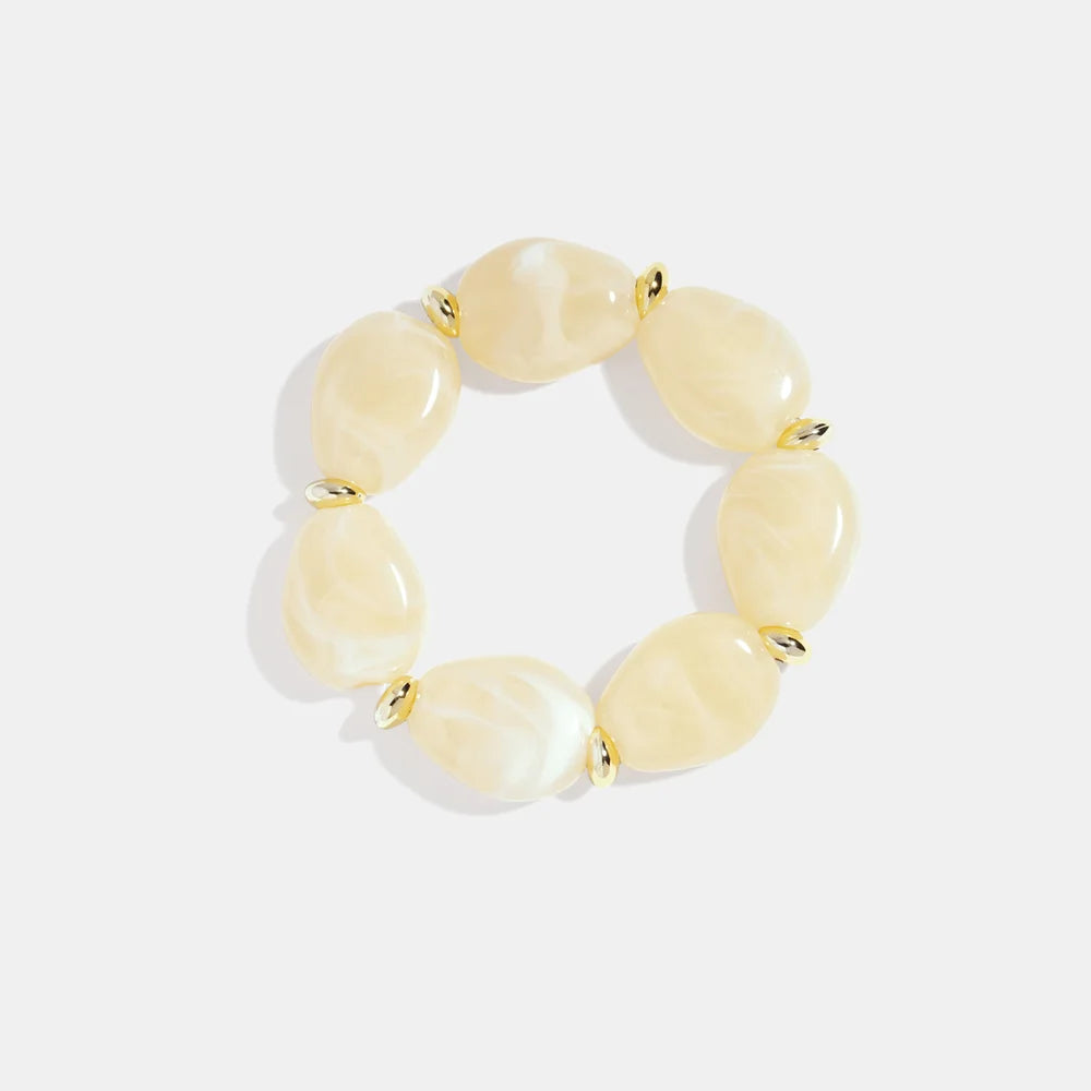 Crèmekleurige squoval kralenarmband met marmer effect en gouden stainless steel accenten, modieuze dames sieraden.