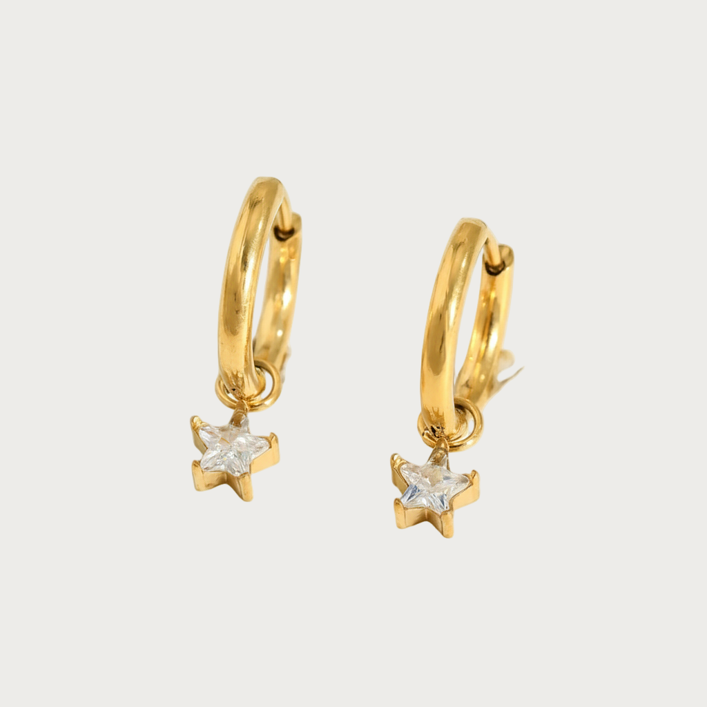 Gouden oorringen met bungelende witte sterhangers, sieraden met ster design en glimmend steentje.