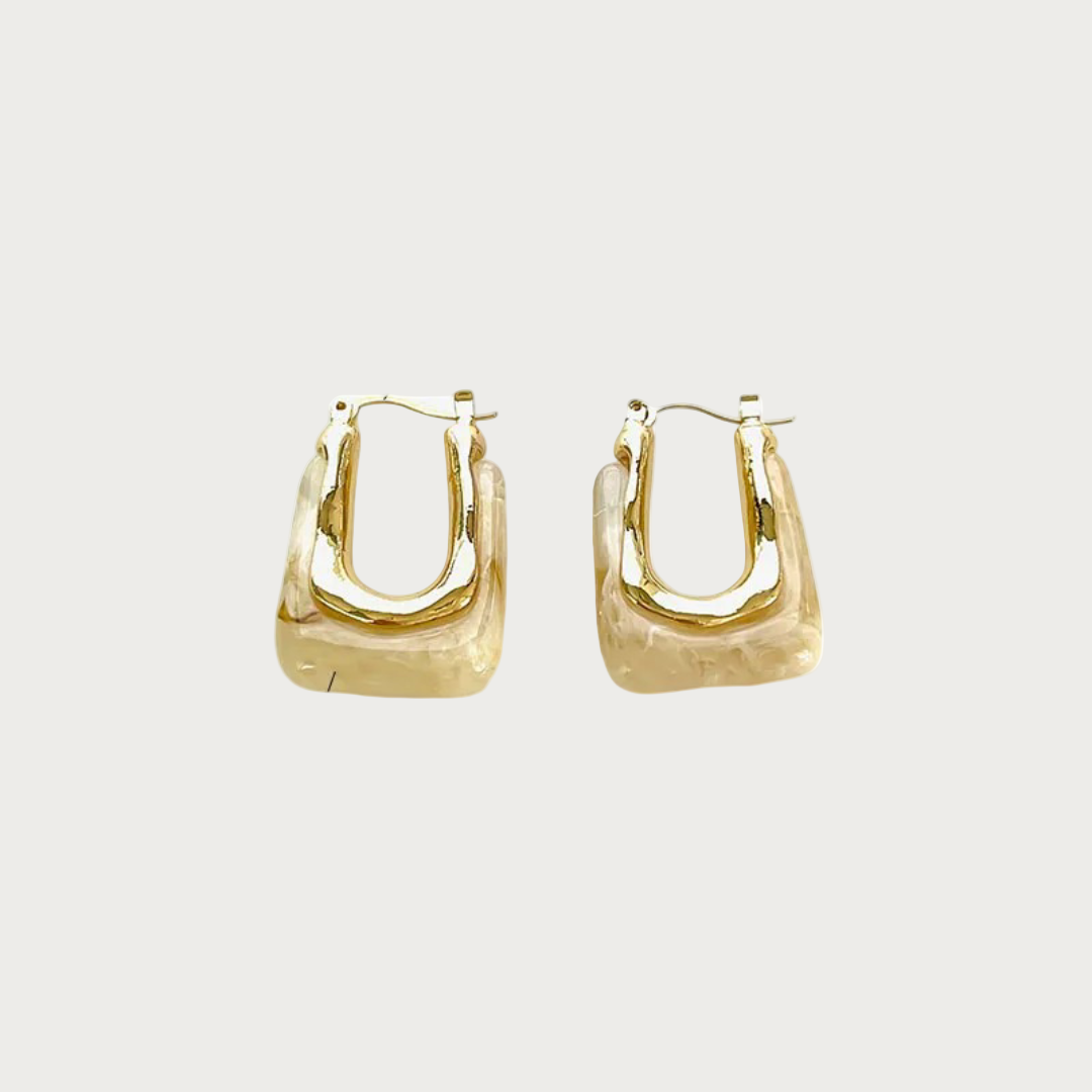 Paar beige oorbellen van stainless steel, met een vierkante, golvende vorm en gouden hardware.