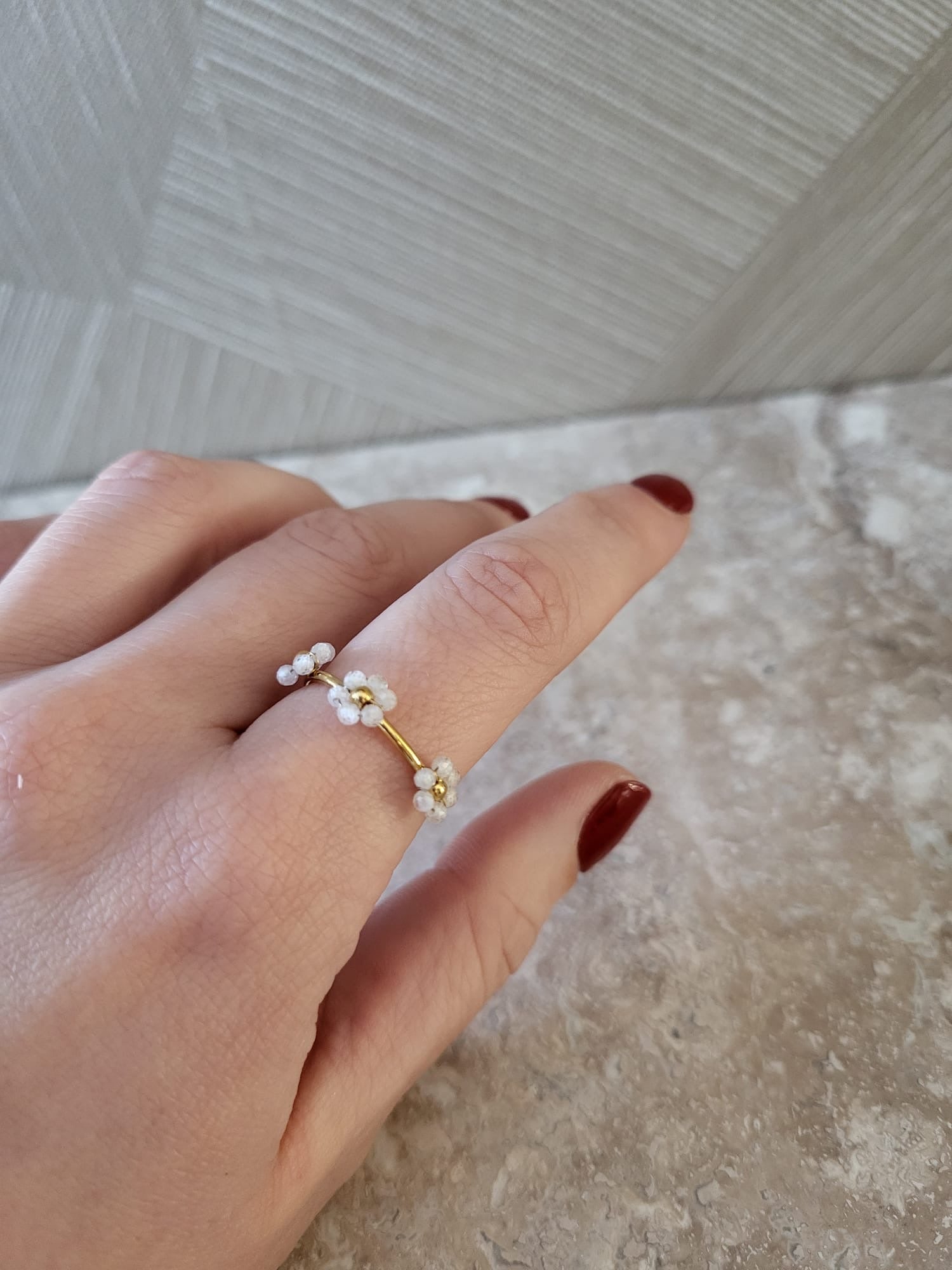 Gouden roestvrijstalen ring met drie delicate witte kraalbloemetjes op de vinger, dames sieraad