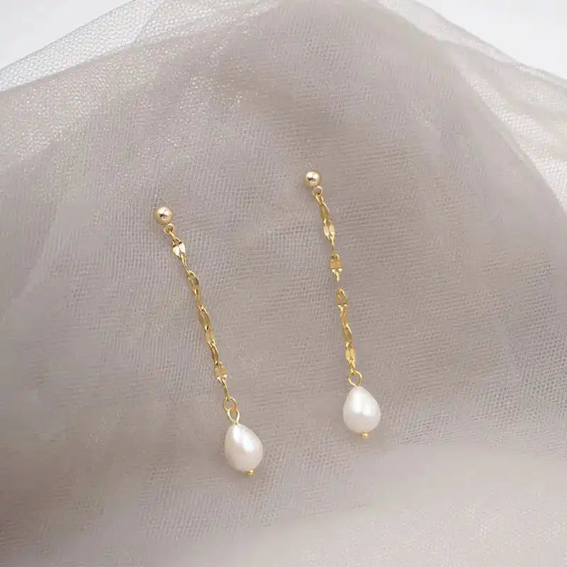 White Pearl Drop oorbellen van stainless steel op zachte stof gepresenteerd. Tijdloze oorbellen met witte parel en verfijnde afwerking.