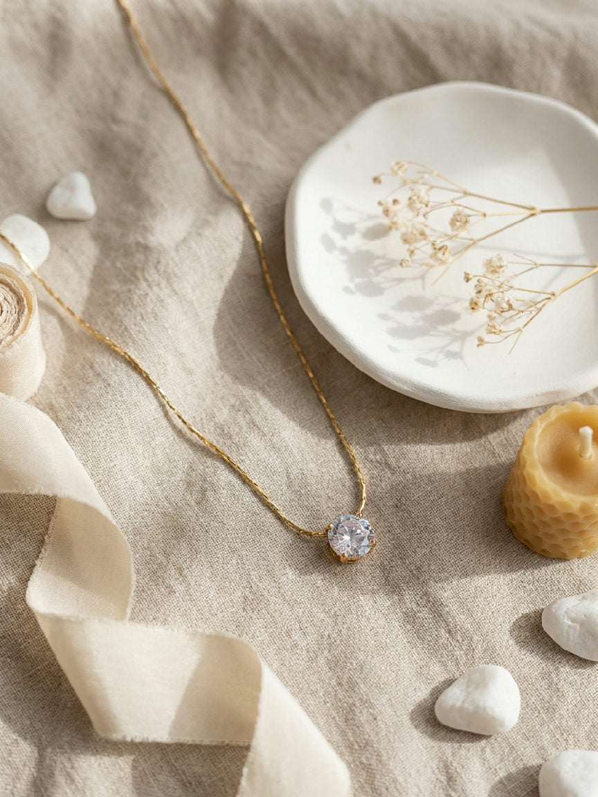 Gouden stainless steel Aurelia ketting met schitterende zirkonia hanger op linnen met lint en waxinelichtje.