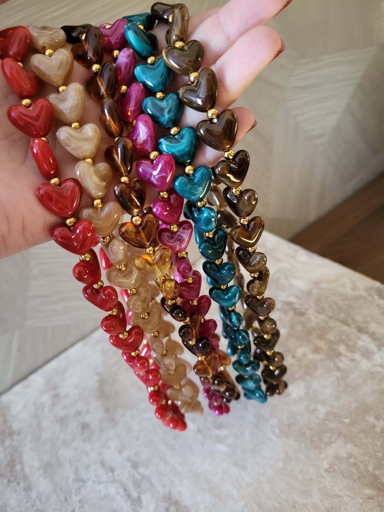 Diverse Milena hartjes kettingen in rood, beige, bruin, roze, groen en paars, van stainless steel, bij elkaar gehouden.