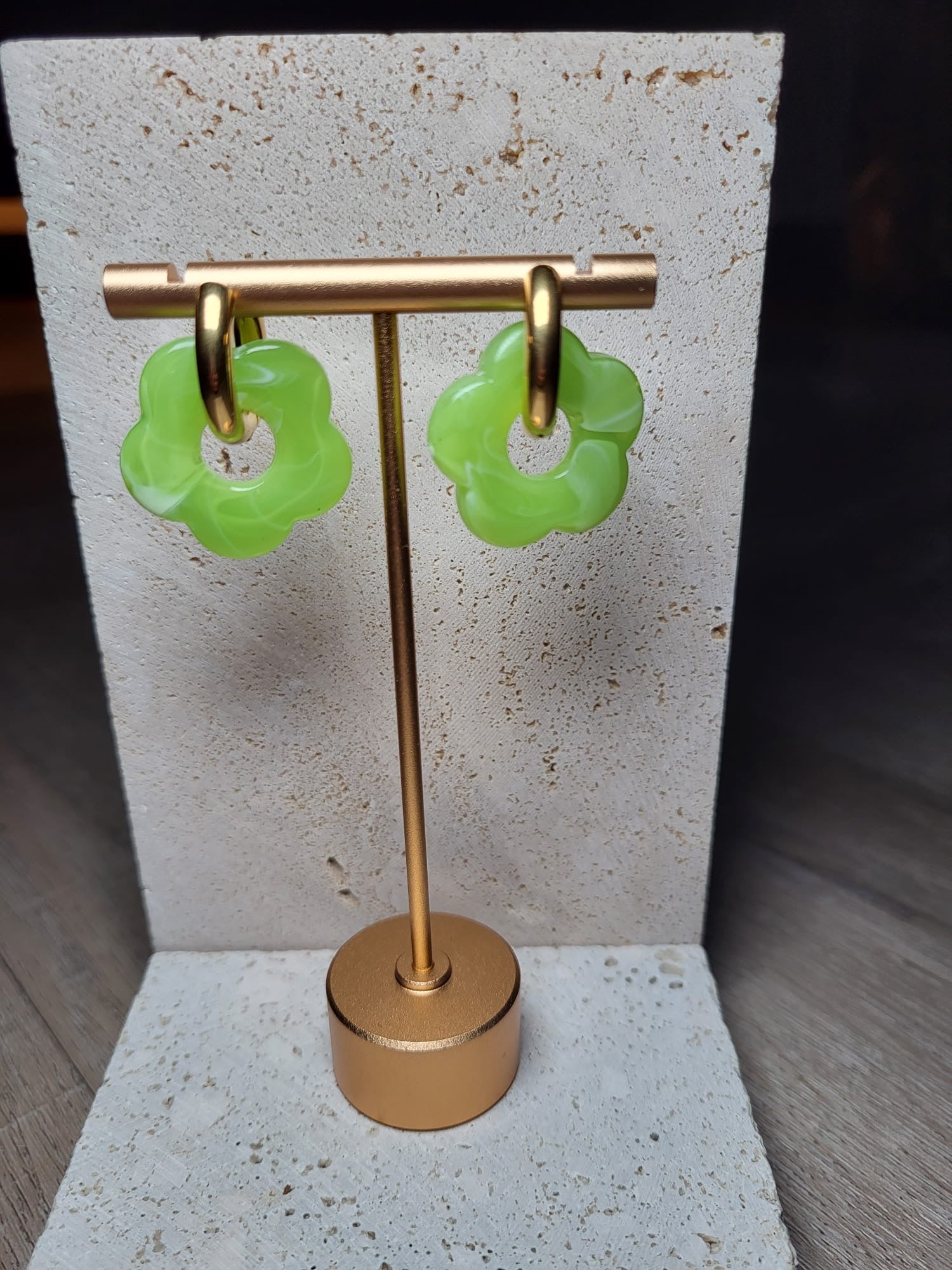 Lichtgroene oorbellen Rosy met bloemvormig design en subtiele witte accenten, hangend aan gouden hangers.