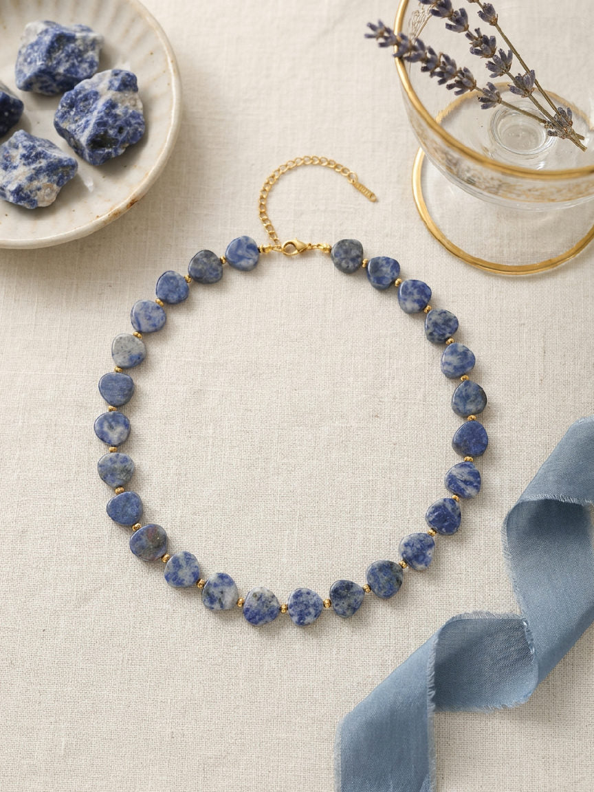 Elena hartvormige sodaliet kralenketting van stainless steel met gouden accenten en verstelbare sluiting op lichte achtergrond