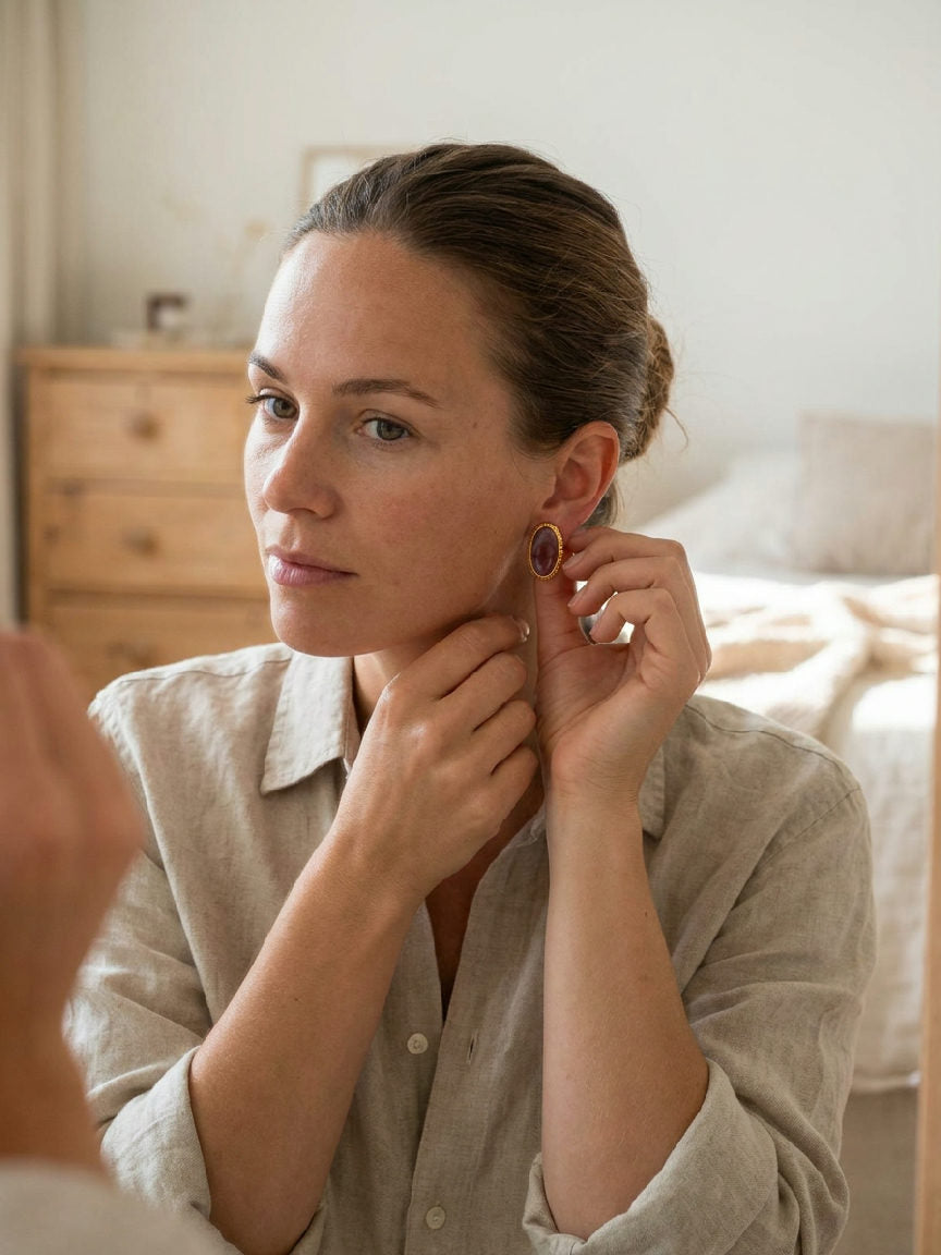 Vrouw draagt elegante golden aura natuursteen oorbellen met glanzend roestvrij staal, haar handen rustend op haar borst, met 
